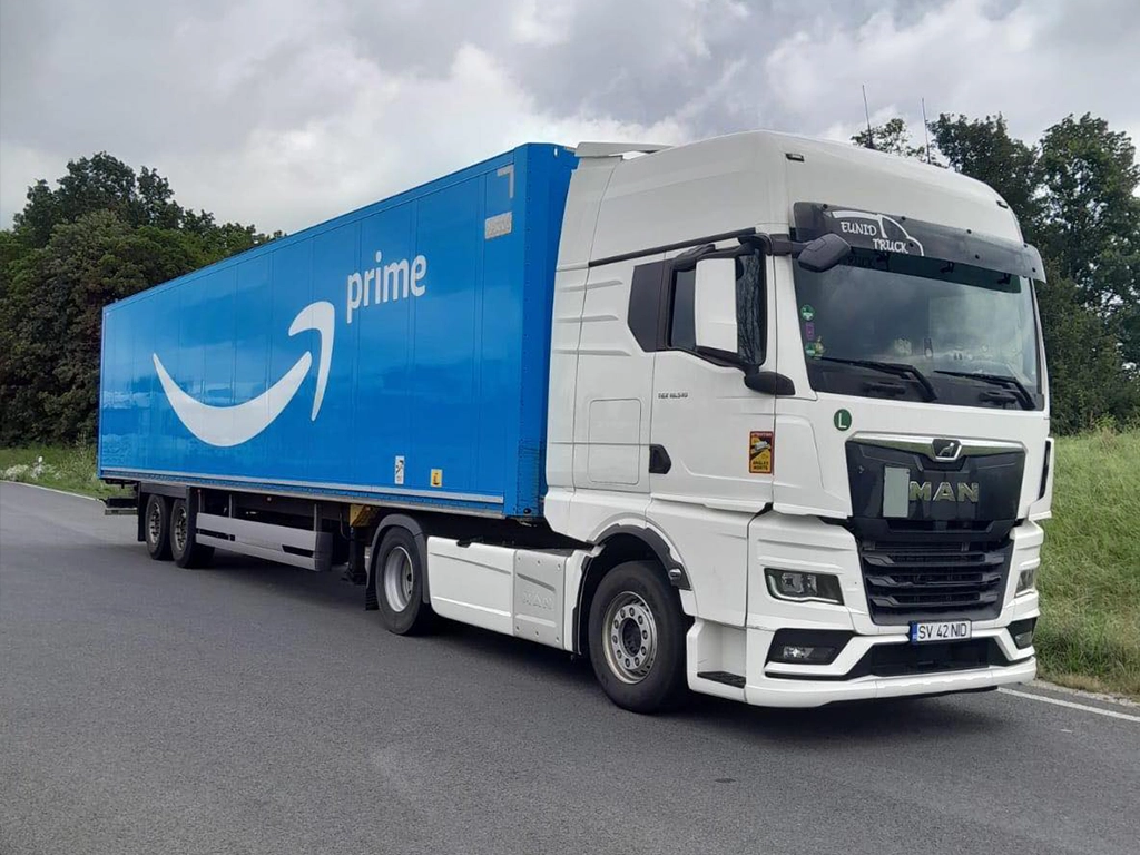 Camion MAN din flota Eunid Truck ce tracteaza o semi-remorca box cu inscriptia Amazon pe ea